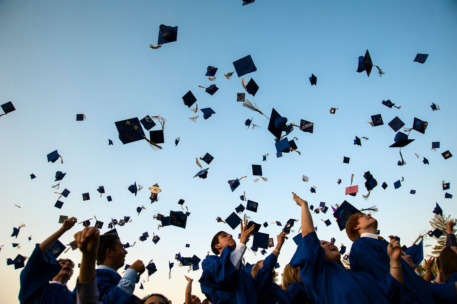 Graduates throwing their caps into a blue sky