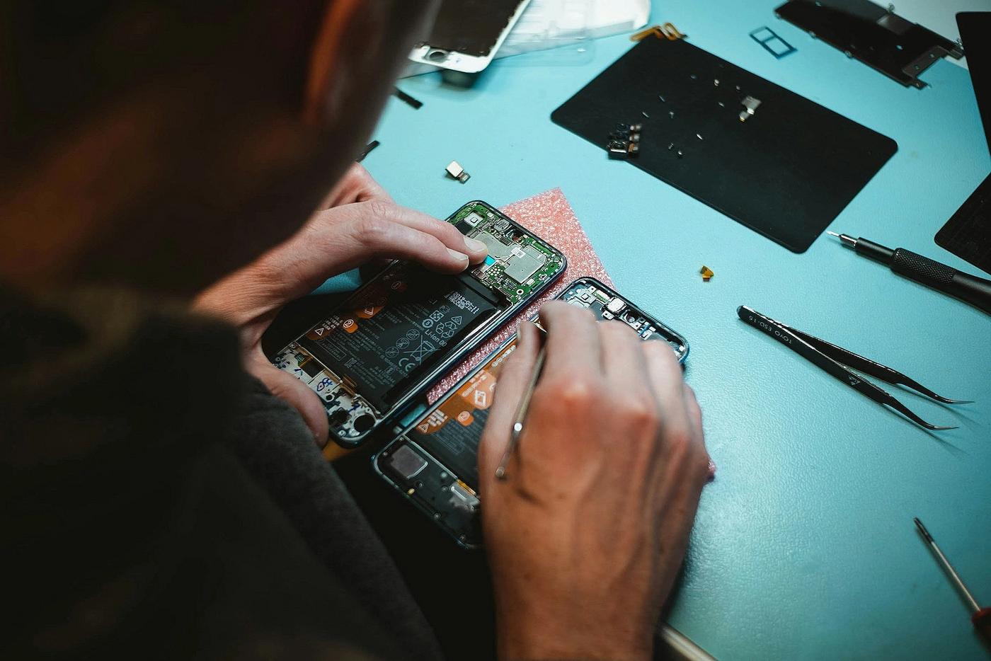 Technician repairing a phone motherboard and battery